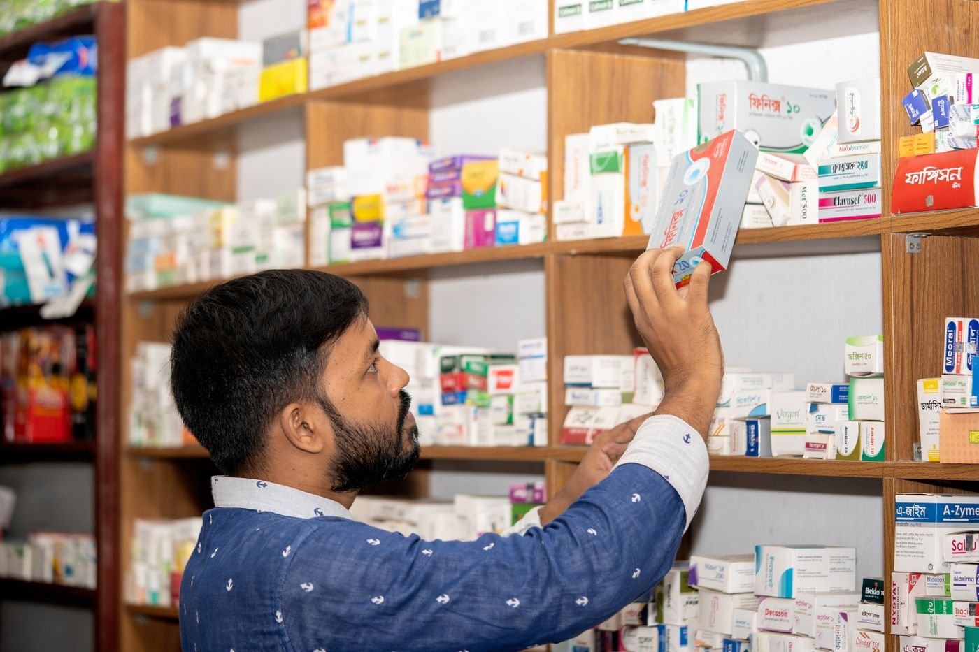 Pharmacist standing beside well-stocked shelves in a modern pharmacy